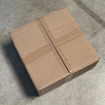 Carton fermé contenant des sachets kraft zip sans fenêtre 750ml, posé sur sol en béton