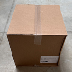 Carton d'expédition fermé contenant 250 sacs papier fenêtre filet écru 1,5kg, posé sur carrelage gris